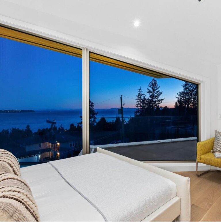 Bedroom with frameless corner windows looking across the water at dusk in a luxury custom home