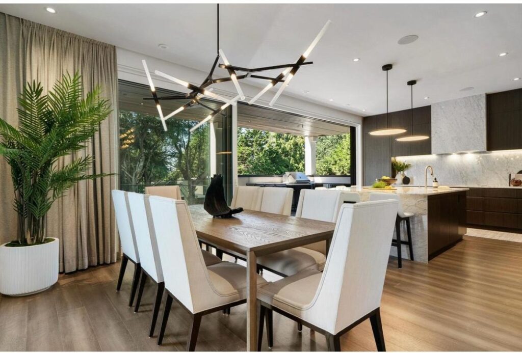 Dining room with a statement chandelier opening to a marble-backsplash kitchen and a covered outdoor living area