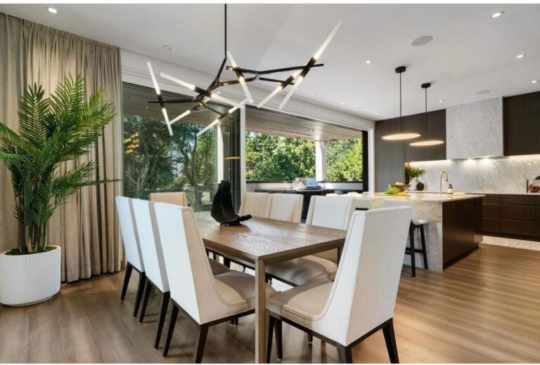 Dining room with a statement chandelier opening to a marble-backsplash kitchen and a covered outdoor living area