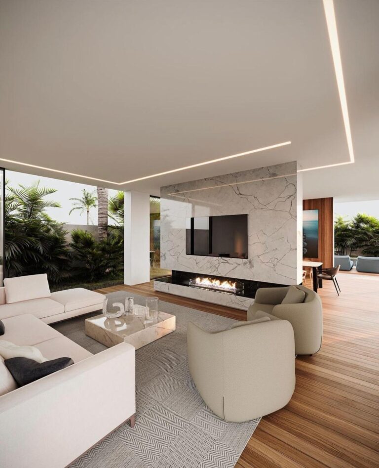 Open-plan luxury living room with a floor-to-ceiling marble fireplace wall, linear ceiling lighting and wide-plank wood floors in a custom home