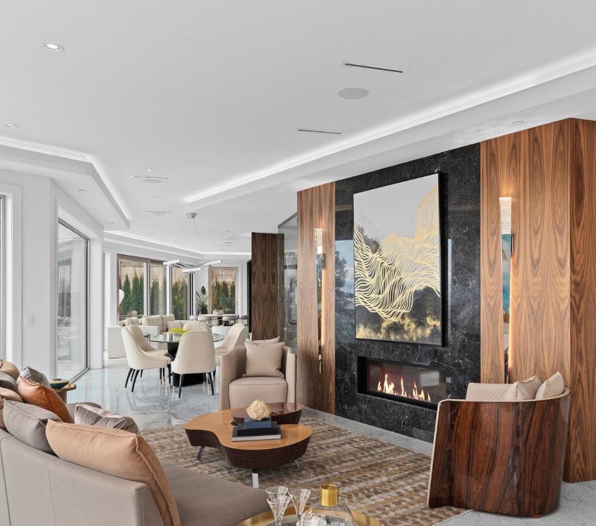 Luxury living room with a black marble fireplace framed by book-matched walnut panelling, open to the dining area