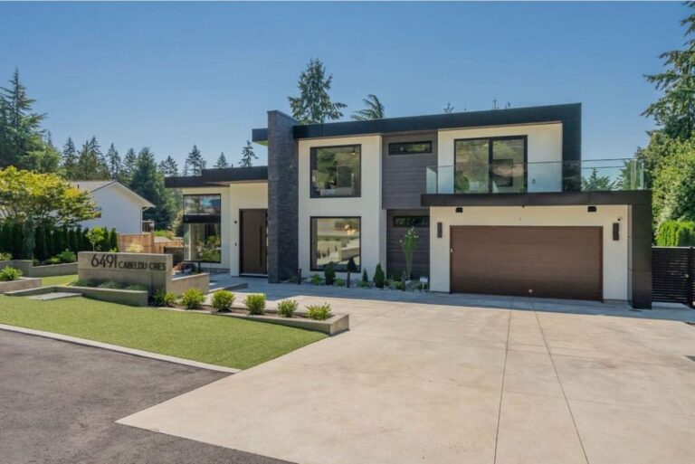 Contemporary two-storey custom home with stucco and stone cladding, a glass-railed balcony and a wide concrete driveway