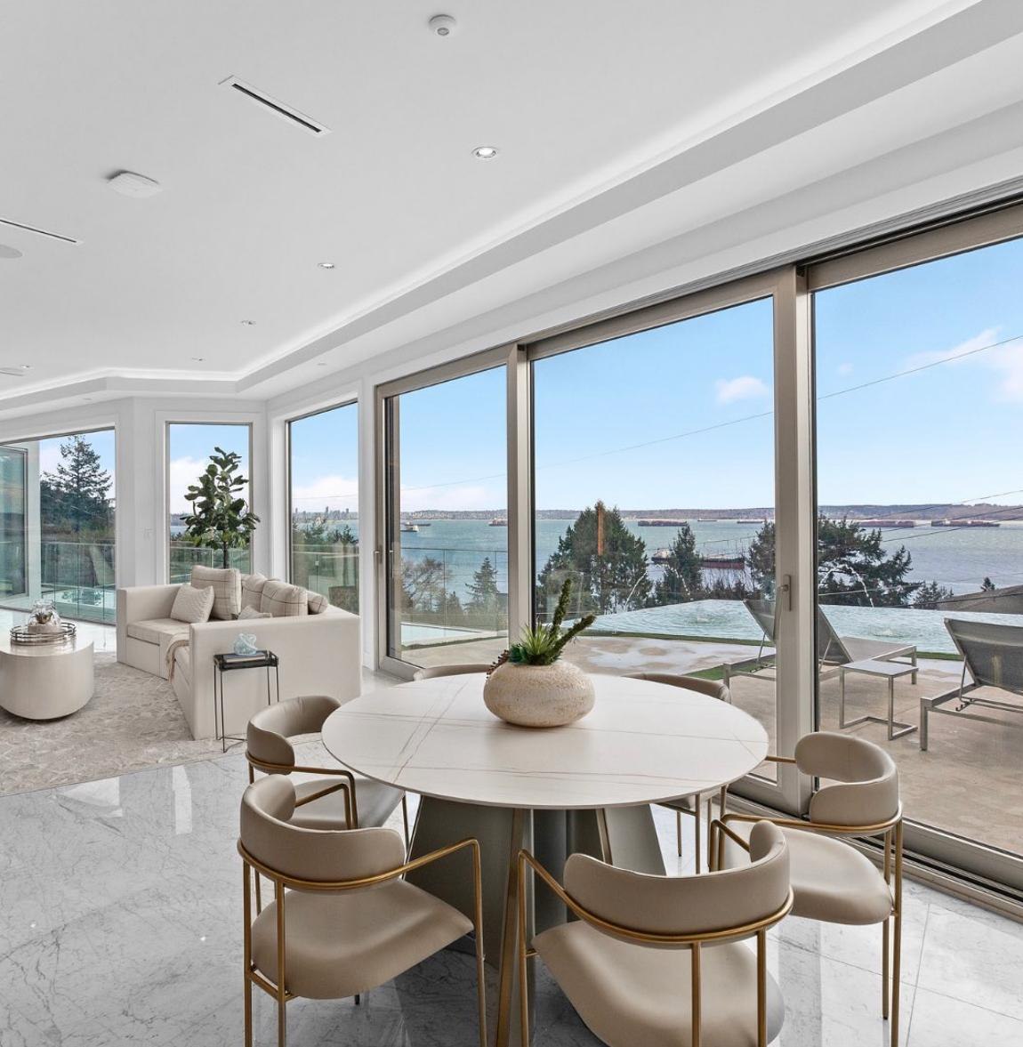 Open-concept dining and living area with marble floors and floor-to-ceiling sliding windows looking over an infinity pool and the ocean